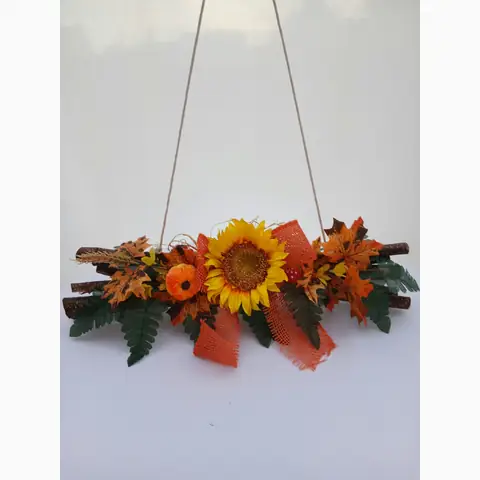 Herbstliche Hängedeko aus Zweigen mit Sonnenblume, Kürbis und Blättern